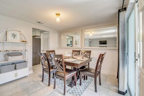 A dining area with a wooden table, six chairs, and a white cabinet with baskets. - 6 Mi to Hudson Beach! Pet-friendly Retreat w/ Yard (Port Richey)