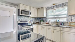 Uma cozinha moderna com armários brancos, eletrodomésticos de aço inoxidável e bancada de granito.