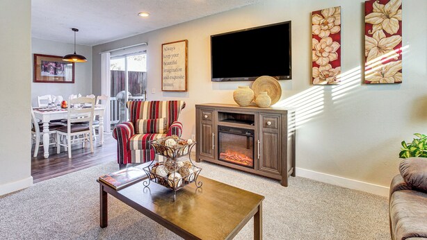 A living room with a fireplace, a television, and artwork on the wall. - Stunning SLC Basecamp: Ski, Explore & Unwind (Taylorsville)