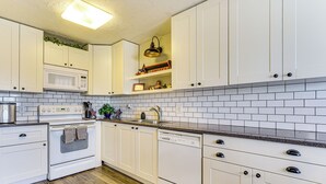 A modern kitchen with white cabinets, a microwave, an oven, and a dishwasher. - Stunning SLC Basecamp: Ski, Explore & Unwind (Taylorsville)