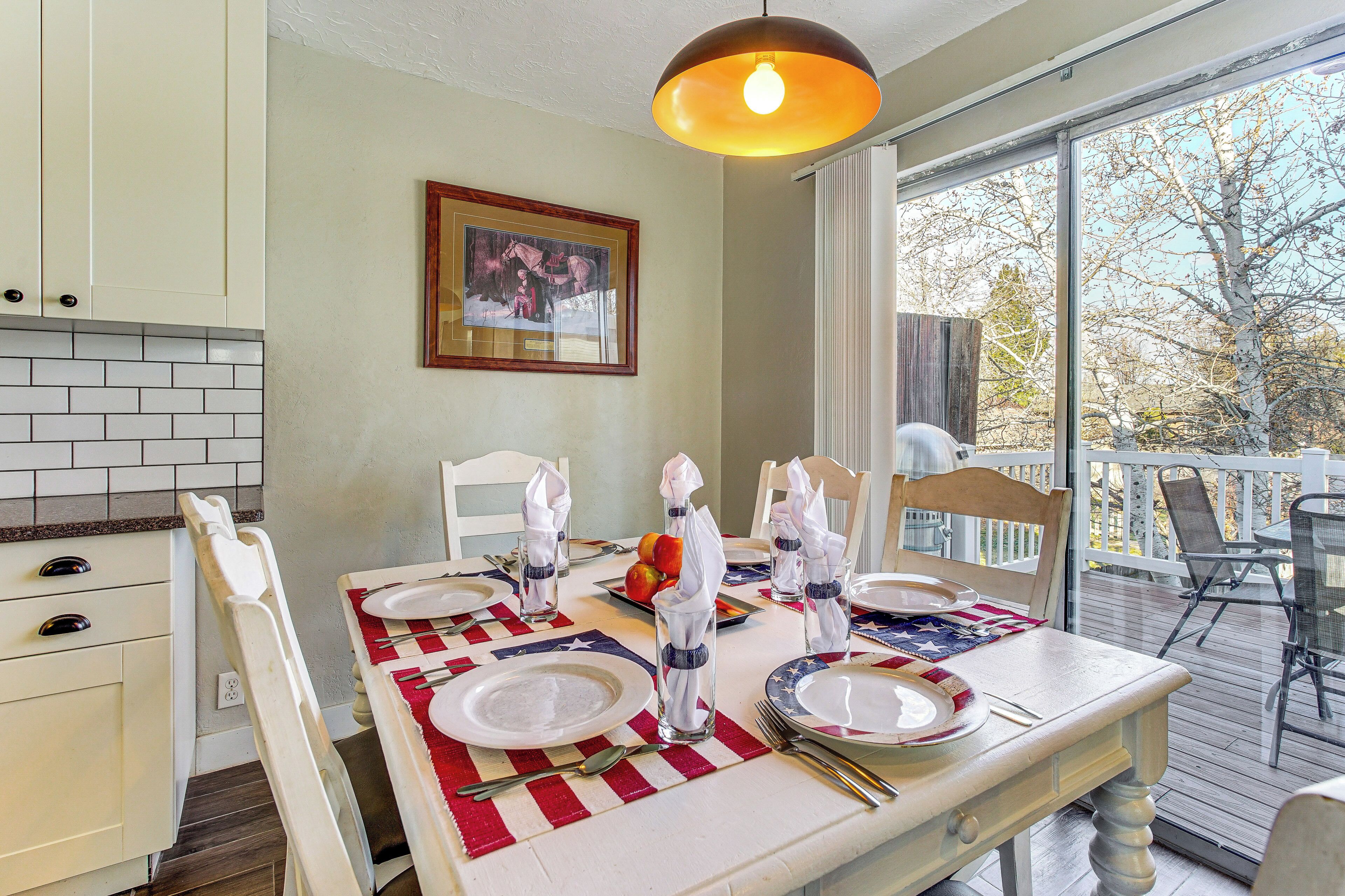 A dining table set with white plates, silverware, and napkins, with a red and white table runner.