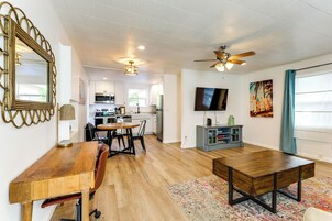 Un amplio salón con una mesa de madera para comer, un sofá y un televisor sobre un mueble.