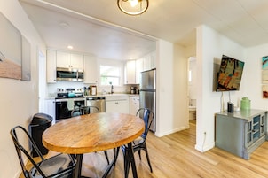 Una cocina moderna con armarios blancos, electrodomésticos de acero inoxidable y una mesa de comedor de madera.