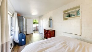 Ein Schlafzimmer mit Bett, Schminktisch, Spiegel und einem Fenster mit Vorhängen.