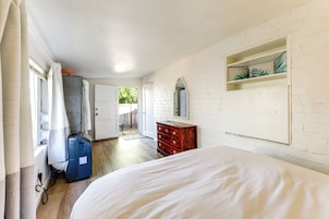 Un dormitorio con cama, cómoda, espejo y ventana con cortinas.