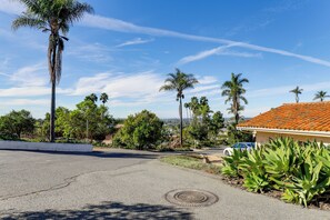 A residential street with palm trees, a white car, and a building with a red-tiled roof. - Private Hilltop Getaway w/ Patio: Dogs Welcome! (Vista)