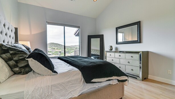 Een slaapkamer met een bed, een kaptafel, een spiegel en een raam met uitzicht.