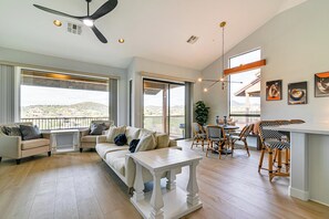 A spacious living room with a large sofa, a dining area with a table and chairs, and a balcony with a view. - Pool Access: Mtn-view Getaway in Fountain Hills! (Fountain Hills)