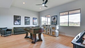 Een ruime kamer met een tafelvoetbaltafel, een bank en een bar.