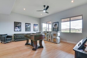 A spacious room with a foosball table, a pool table, a bar area, and large windows offering a view of the landscape. - Pool Access: Mtn-view Getaway in Fountain Hills! (Fountain Hills)