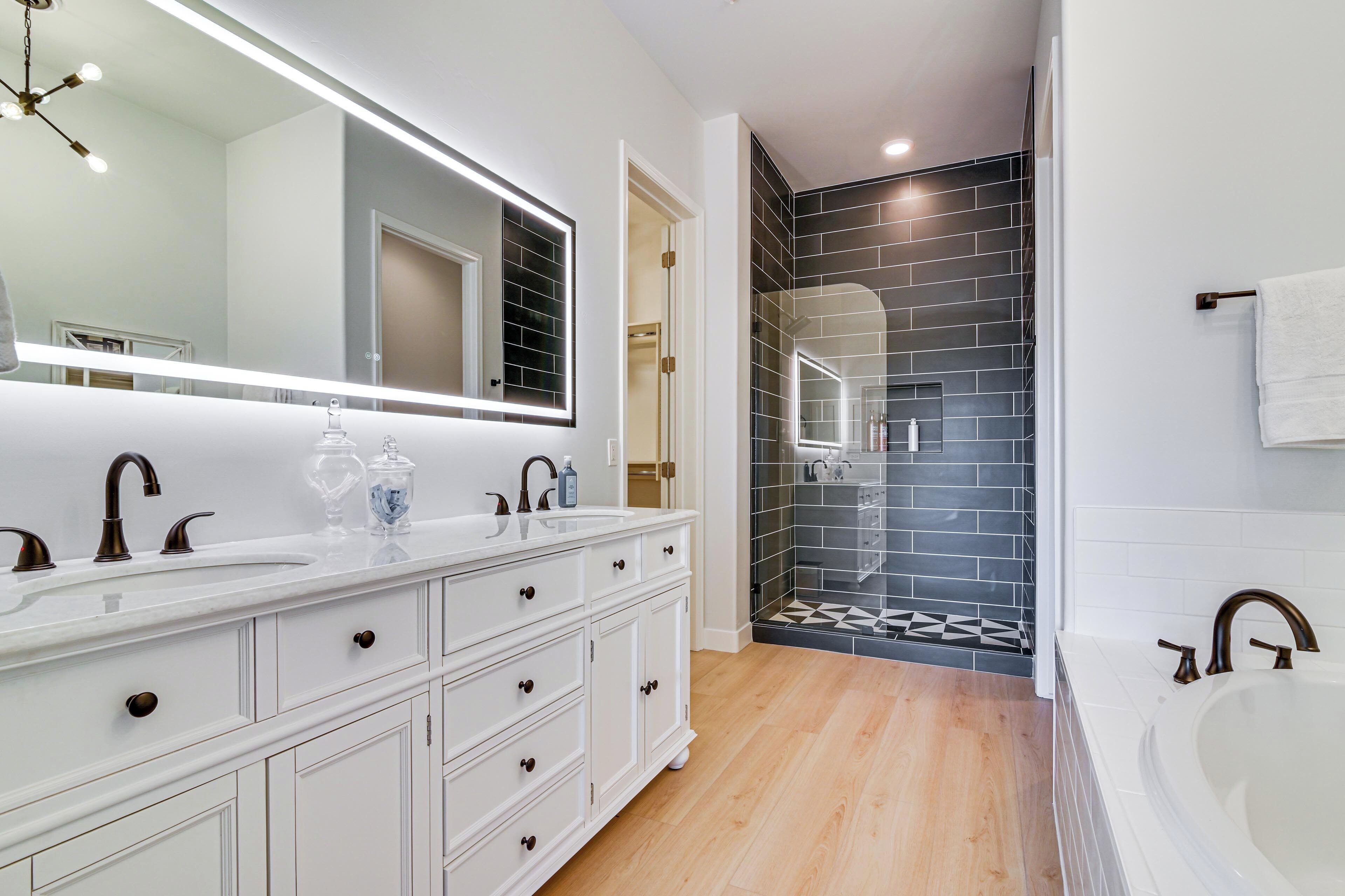 A modern bathroom with a large mirror, white vanity, and a separate shower area.