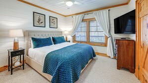 Ein Schlafzimmer mit einem Bett, einem Nachttisch, einem Fernseher und einem Fenster mit Vorhängen.