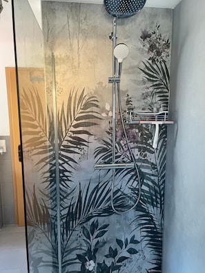 Eine Dusche mit Glastür, Duschkopf und Handbrause.