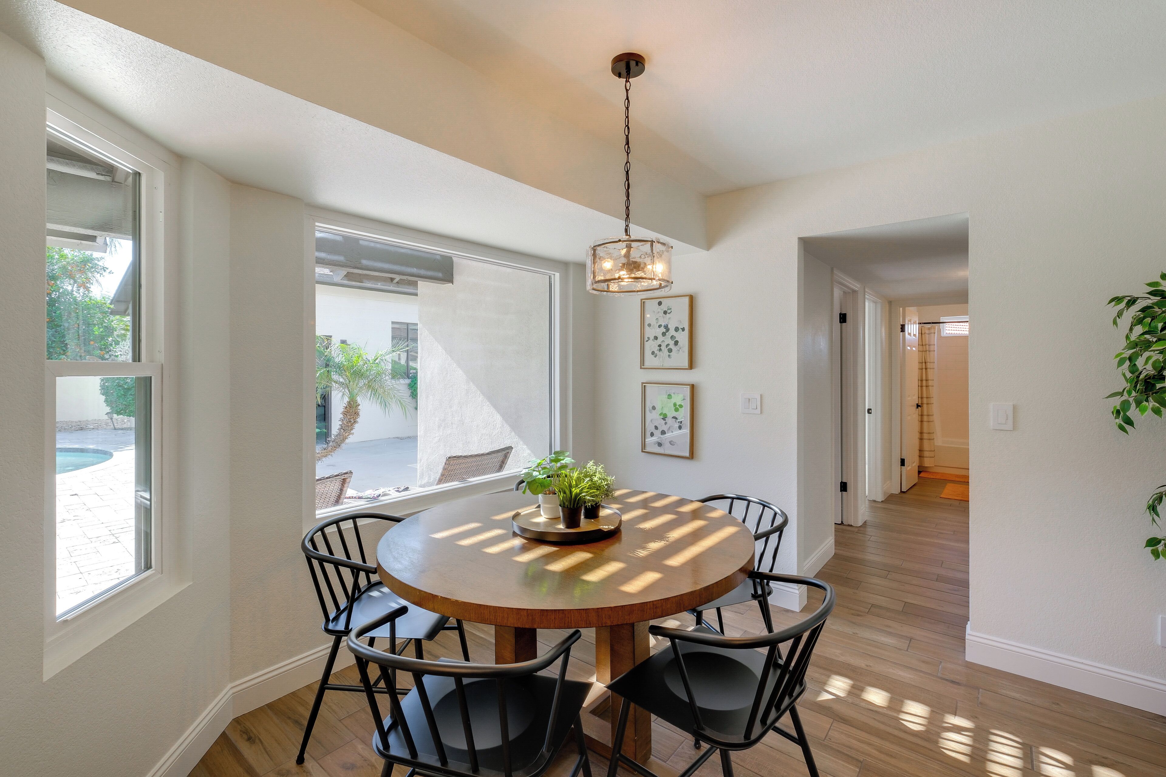 A dining area with a round table, black chairs, and a hanging light fixture.