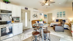 A compact kitchen with white cabinets, a microwave, and an oven. There is a dining area with a round table and stools. A ceiling fan is visible above the dining area. - 4 Mi to Dtwn! Grand Junction Stay w/ Private Pool (Grand Junction)