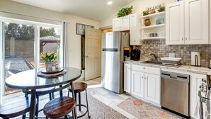 A modern kitchen with white cabinets, stainless steel appliances, and a glass dining table with bar stools. - 4 Mi to Dtwn! Grand Junction Stay w/ Private Pool (Grand Junction)