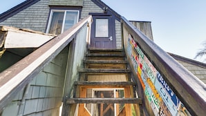 Un escalier en bois mène à une porte dotée d’une fenêtre, le tout étant entouré d’un mur orné de divers panneaux.