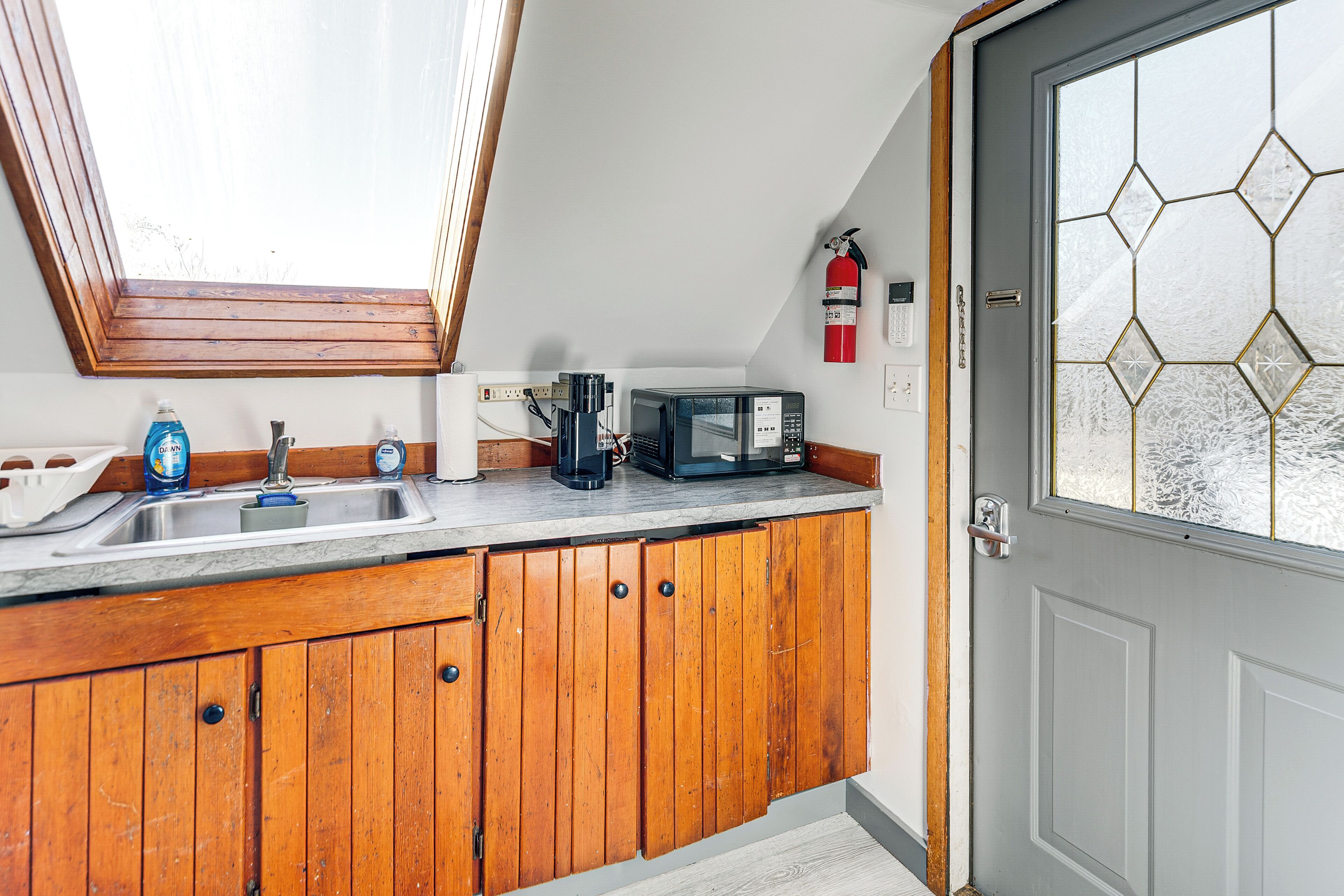 A kitchen with wooden cabinets, a sink, a coffee maker, and a microwave.