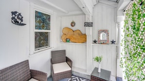 A cozy room with wicker furniture, a decorative wall, and a hanging sign. - Hike, Fish & Ski: Riverside Barn Loft in Lee (South Lee)