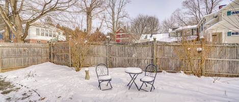 Patio cubierto de nieve con dos sillas de metal y una mesa pequeña.