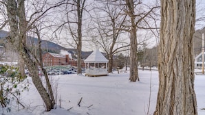 A gazebo in a snowy park with bare trees and distant buildings. - Hike, Fish & Ski: Riverside Barn Loft in Lee (South Lee)