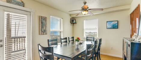 A dining area with a wooden table, six chairs, a ceiling fan, and a small decorative item on the wall.