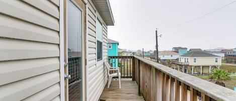 A wooden deck with a chair, a window, and a view of neighboring houses.
