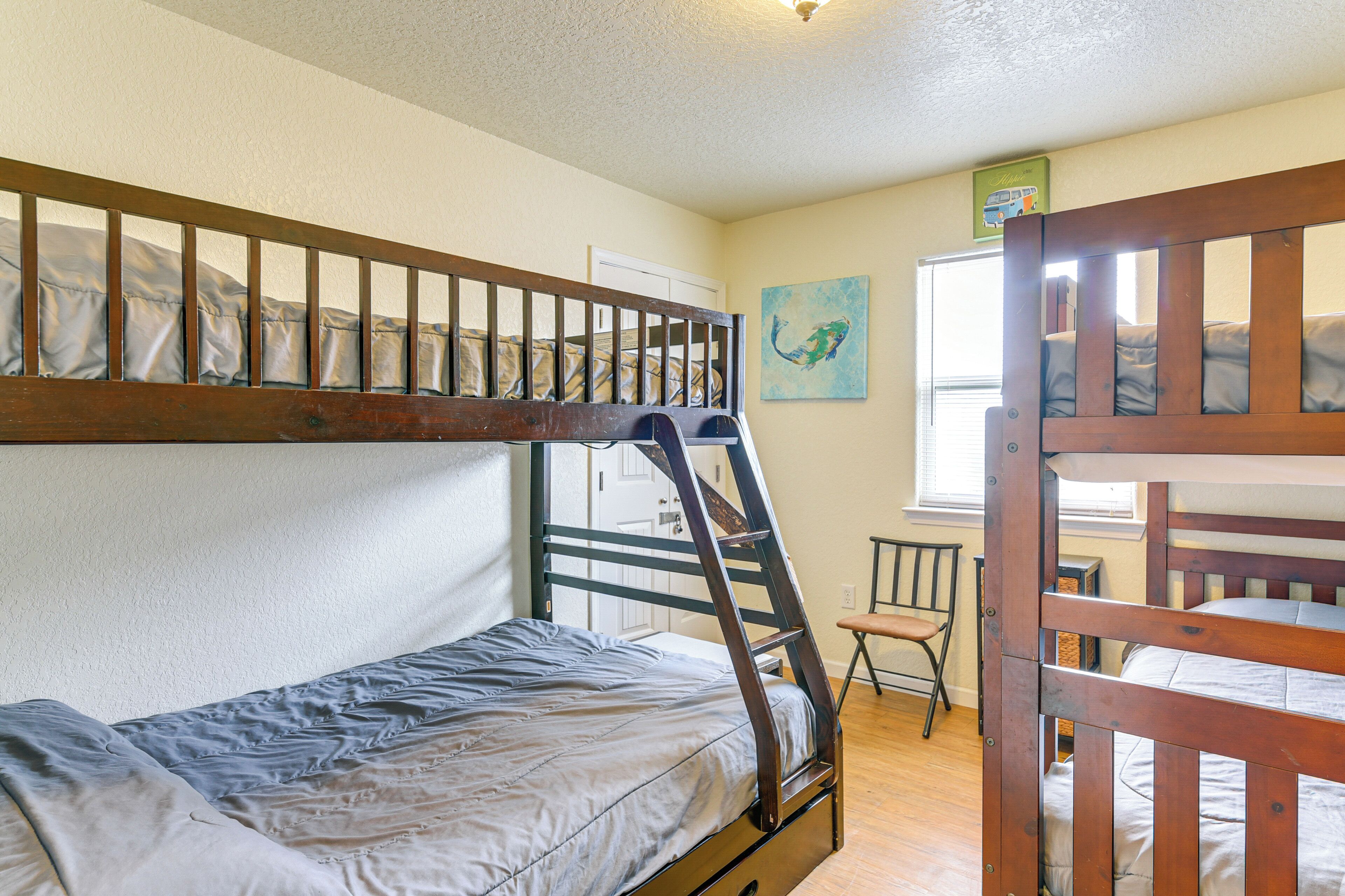 Habitación con literas, una escalera de madera, una silla y un cuadro en la pared.