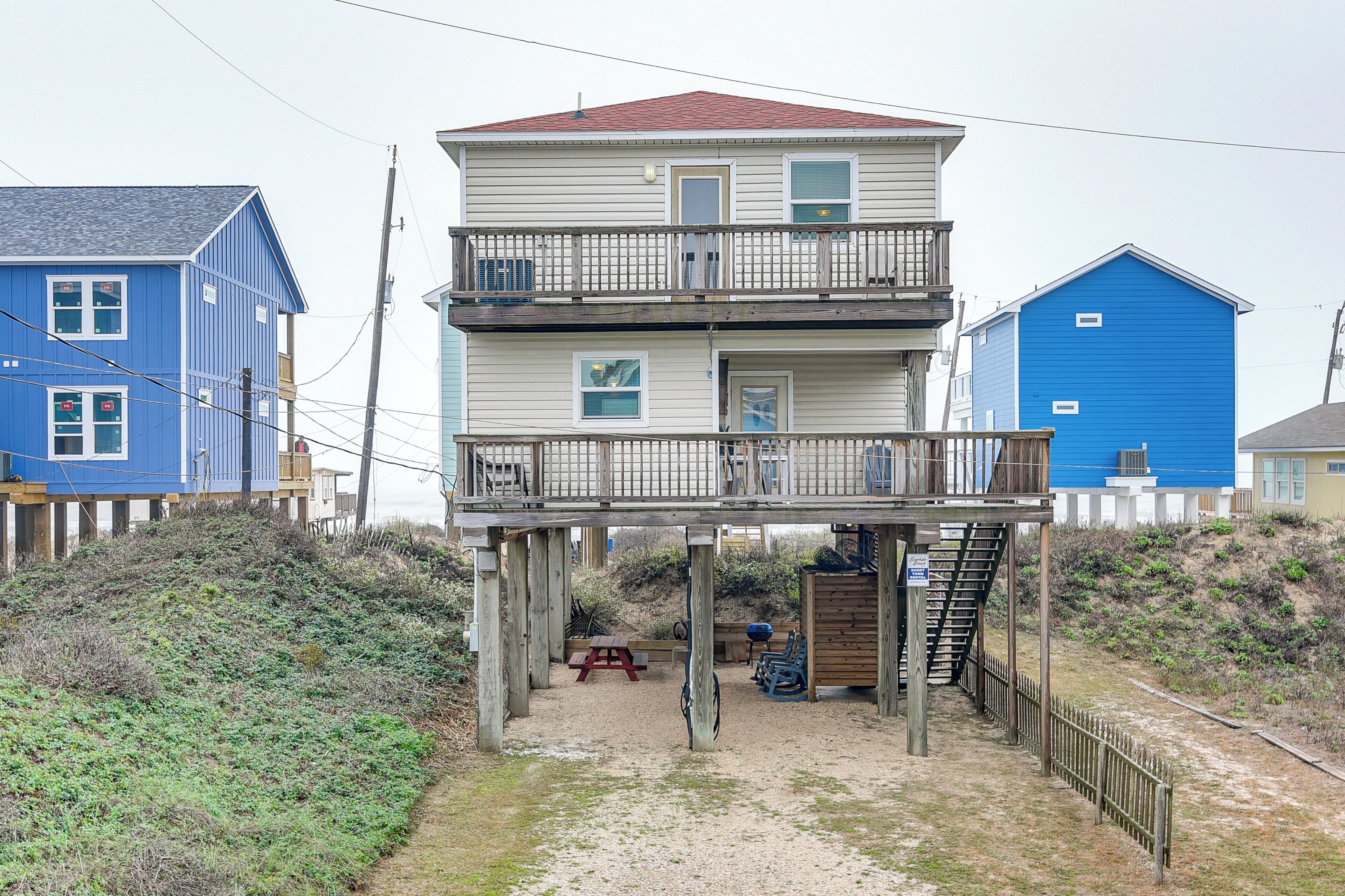 A multi-story building with a balcony, a wooden deck, and a staircase leading to the upper floor.