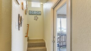 A staircase with a 'BEACH' sign above it, leading to a wooden deck outside. - Daves Waves Pet-friendly Home in Surfside Beach (Freeport)