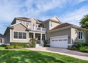 Ein zweistöckiges Haus mit Veranda, Garage und gepflegtem Rasen.