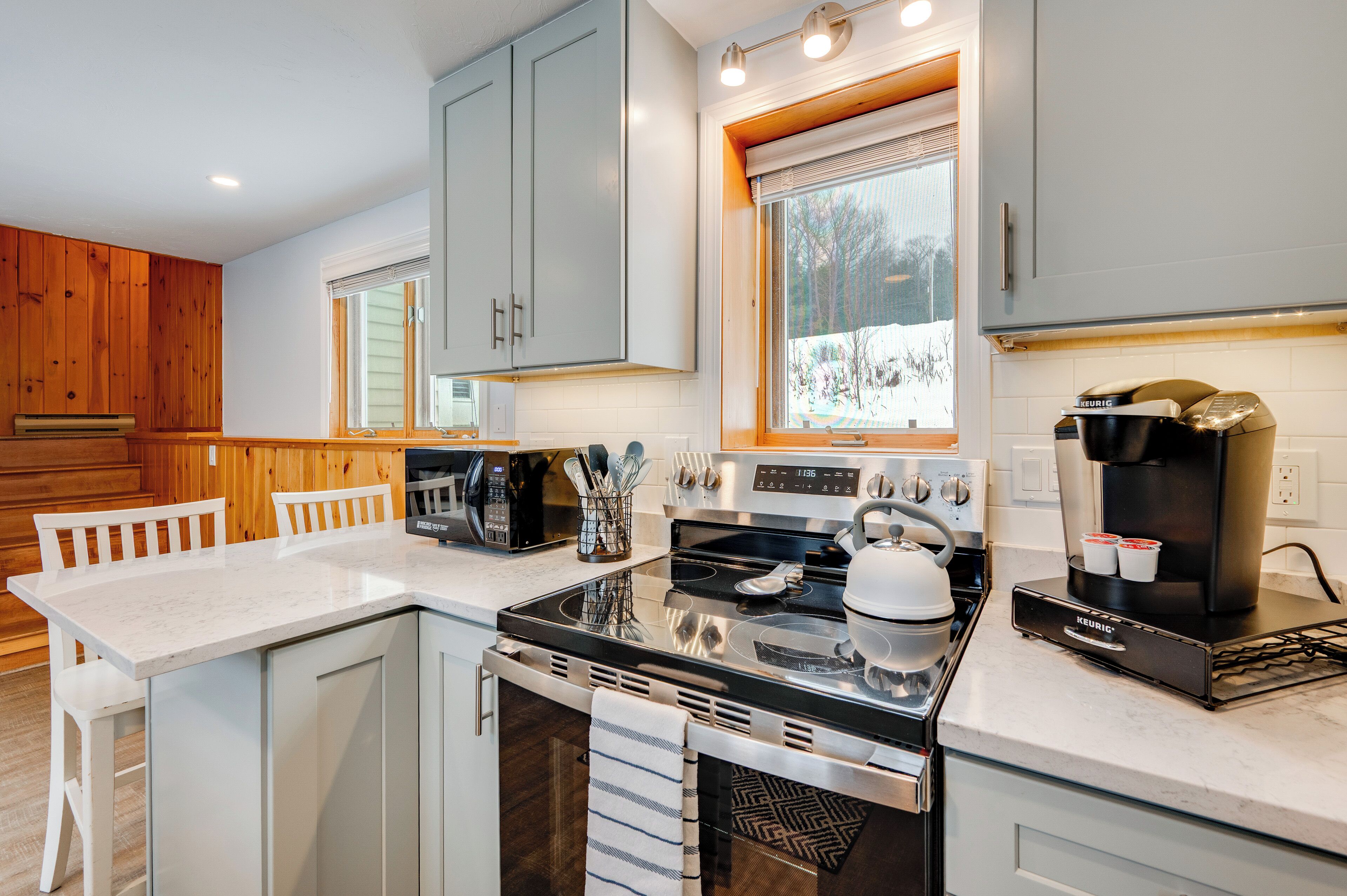 A modern kitchen with grey cabinets, a black stove, and a coffee maker.