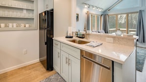 Una cocina moderna con lavavajillas integrado, un refrigerador y ventana con vista a una terraza.