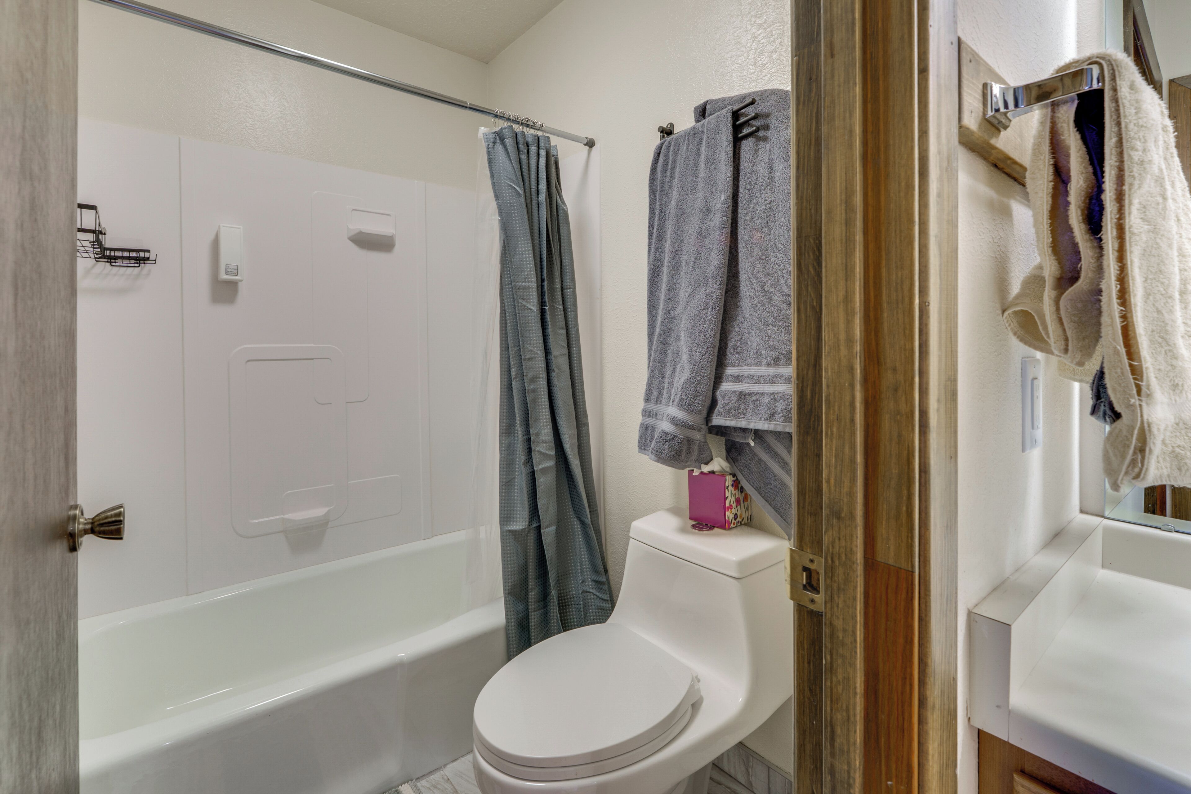 A bathroom with a white bathtub, a toilet, and a shower curtain.