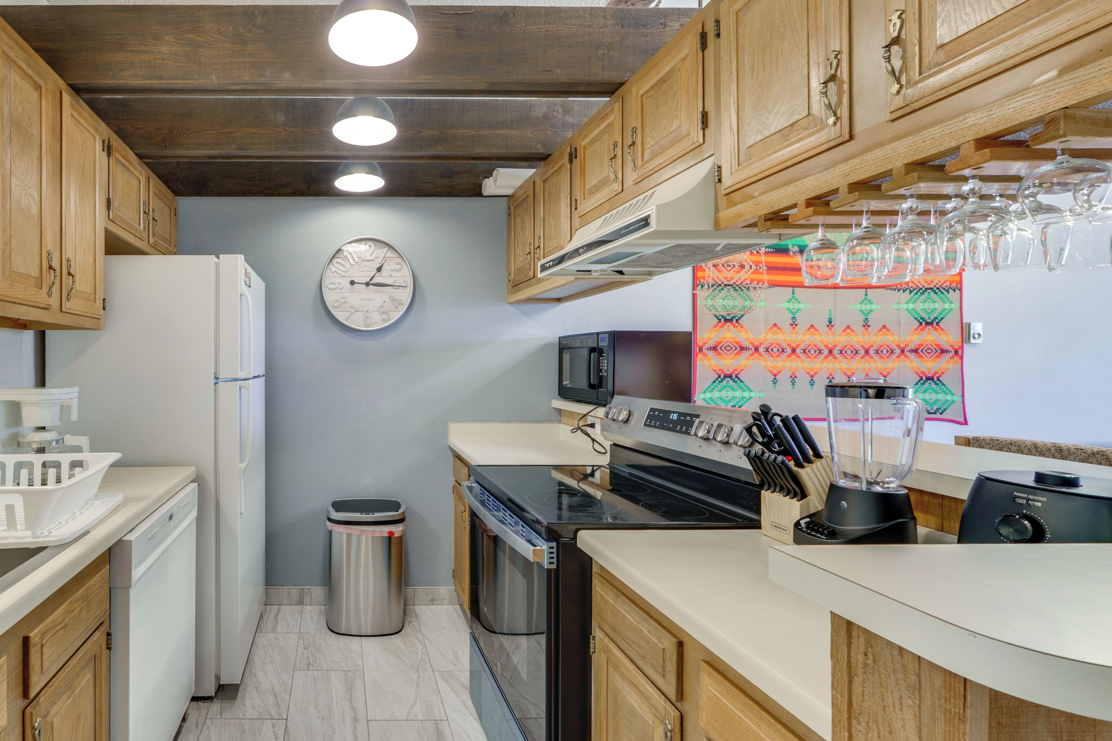 A kitchen with wooden cabinets, a white refrigerator, a microwave, a stove, and a blender.