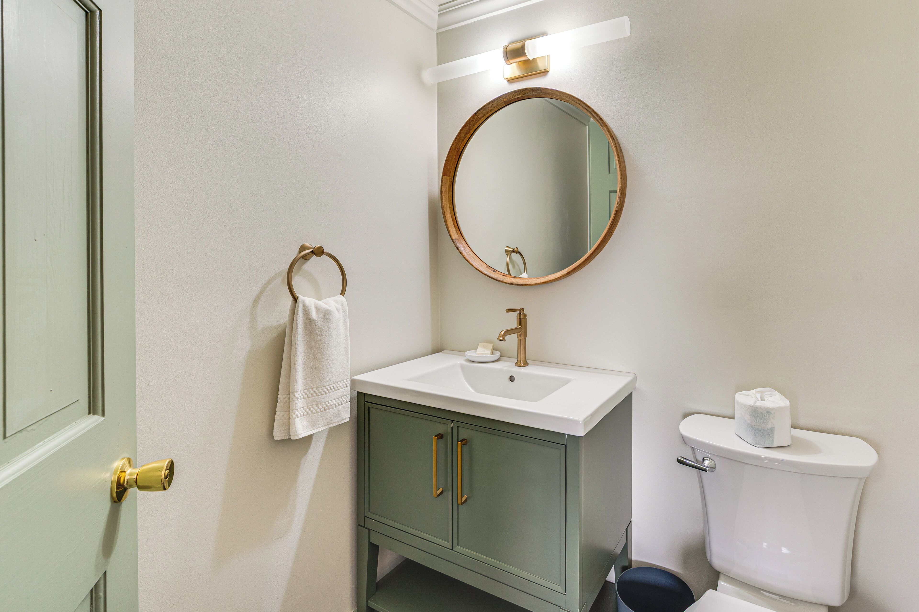 Ein Badezimmer mit einem weißen Waschbecken, einem runden Spiegel und einer Toilette.