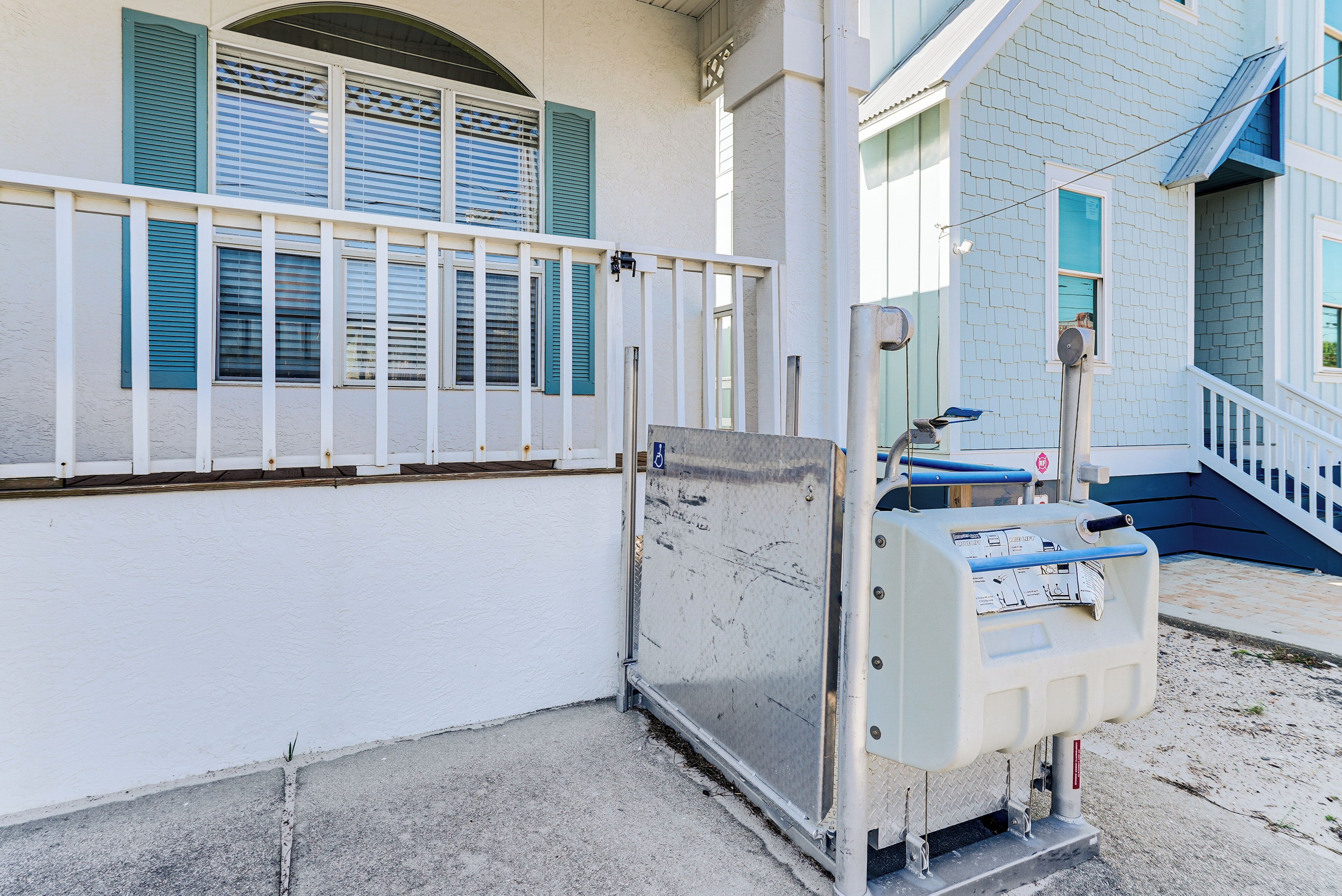 A building with a white exterior, blue shutters, and a metal gate.