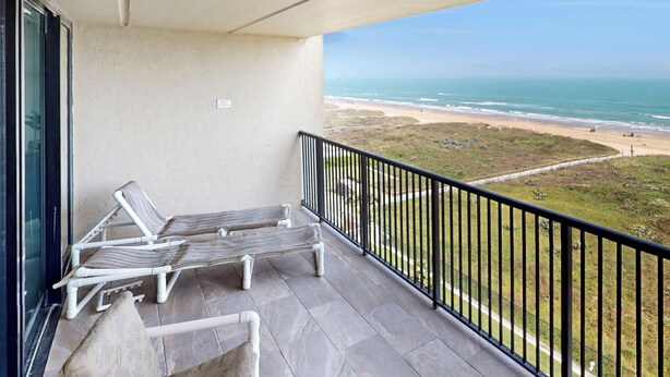A balcony with two lounge chairs and a small table, overlooking a beach with a clear view of the ocean and sandy shore. - Shorefront 2br, Luxe Perks: Suntide III - Unit 704 (South Padre Island)