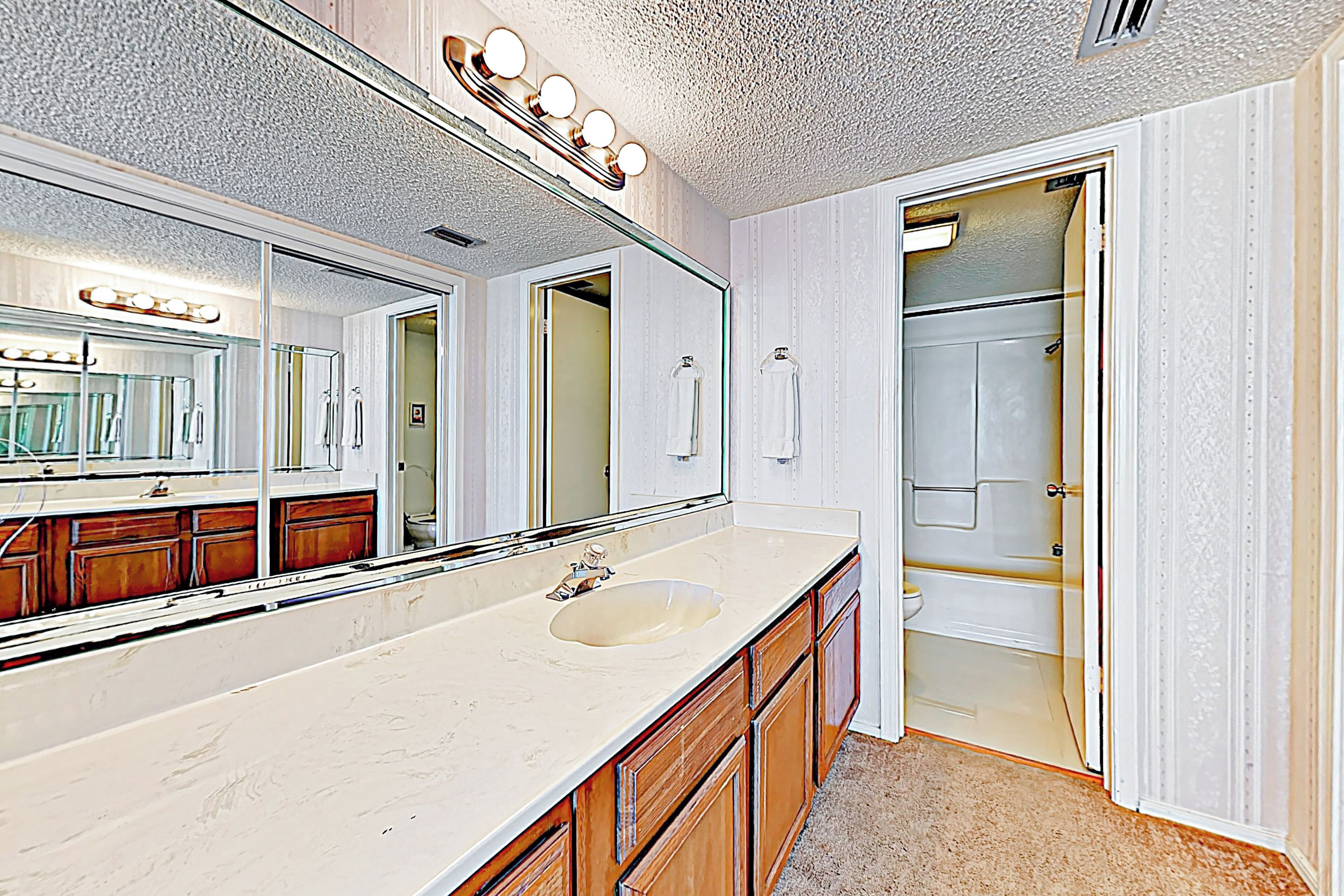 A bathroom with a large mirror, vanity, and a walk-in shower.