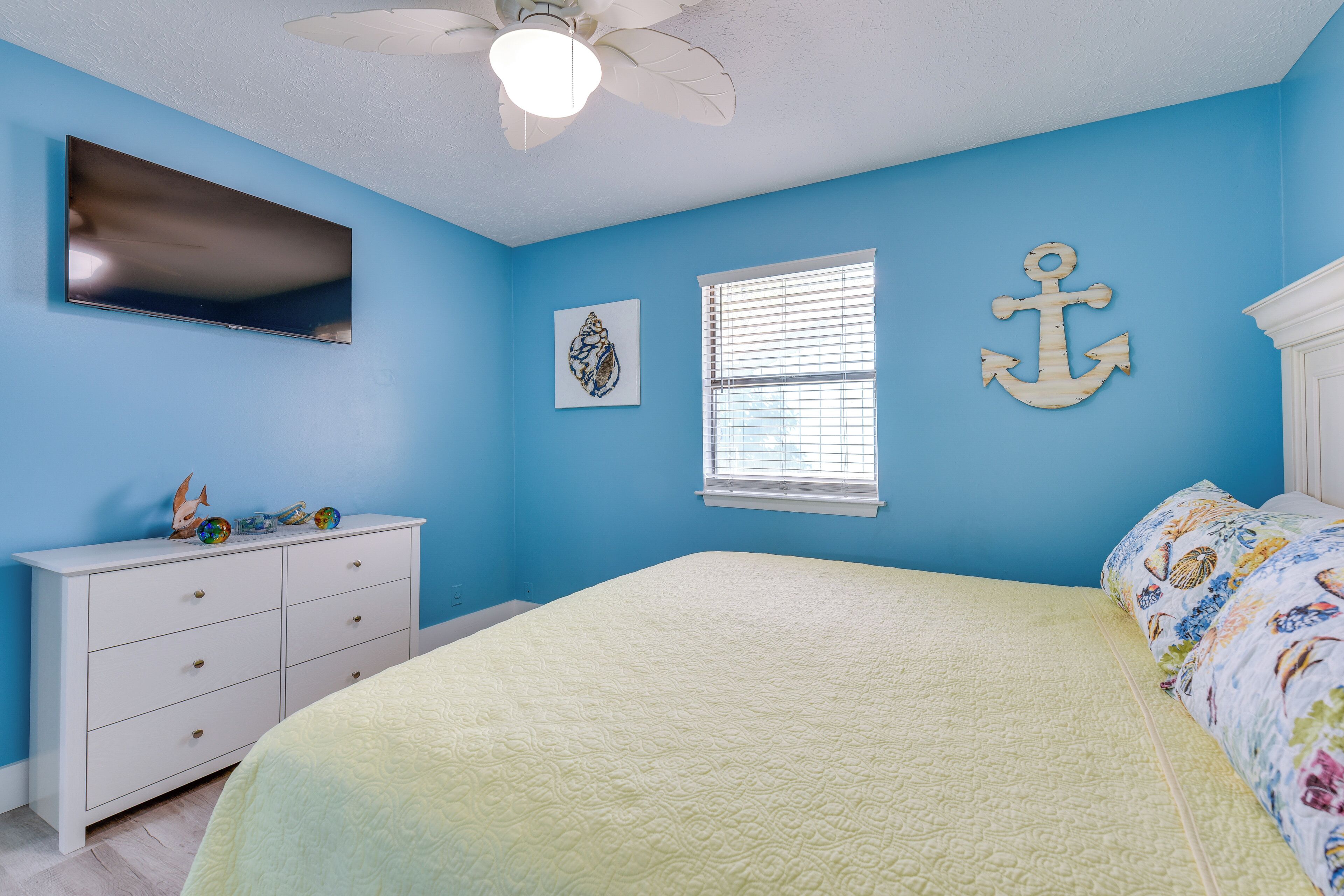 A bedroom with a bed, a dresser, a television, and decorative items.