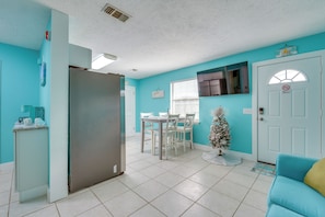 A bright kitchen with a refrigerator, a dining table with chairs, a small Christmas tree, and a teal-colored wall. - Walk to Beach & Rick Seltzer Park! PCB Getaway (Panama City Beach)