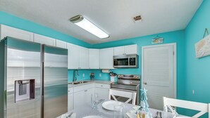 Een moderne keuken met witte kasten, roestvrijstalen apparatuur en een wand in blauwgroen.
