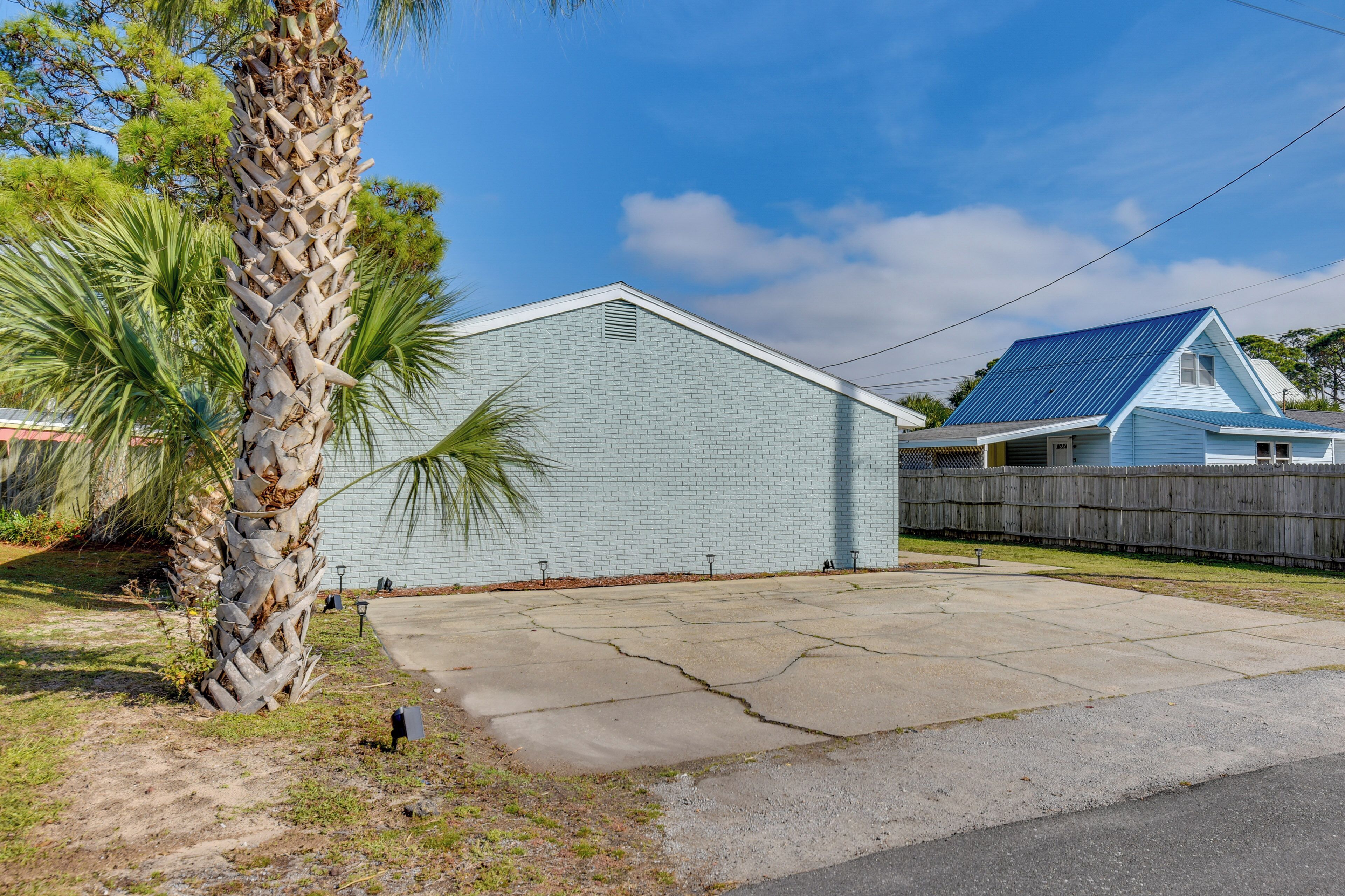 A single-story building with a light blue exterior, a concrete driveway, and a wooden fence.