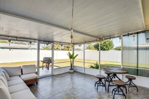 Un'area patio coperta con un divano componibile, un tavolo rotondo con sgabelli e una pianta in vaso.