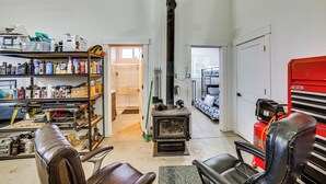 A workshop with a wood stove, shelves with tools and supplies, and a red fire extinguisher. - Sportsman's Paradise! St Maries Stay Near Hunting (St. Maries)
