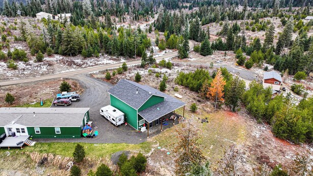 A large green building with a covered parking area, surrounded by a forested landscape and a road. - Sportsman's Paradise! St Maries Stay Near Hunting (St. Maries)
