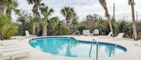 A swimming pool with white lounge chairs and palm trees.