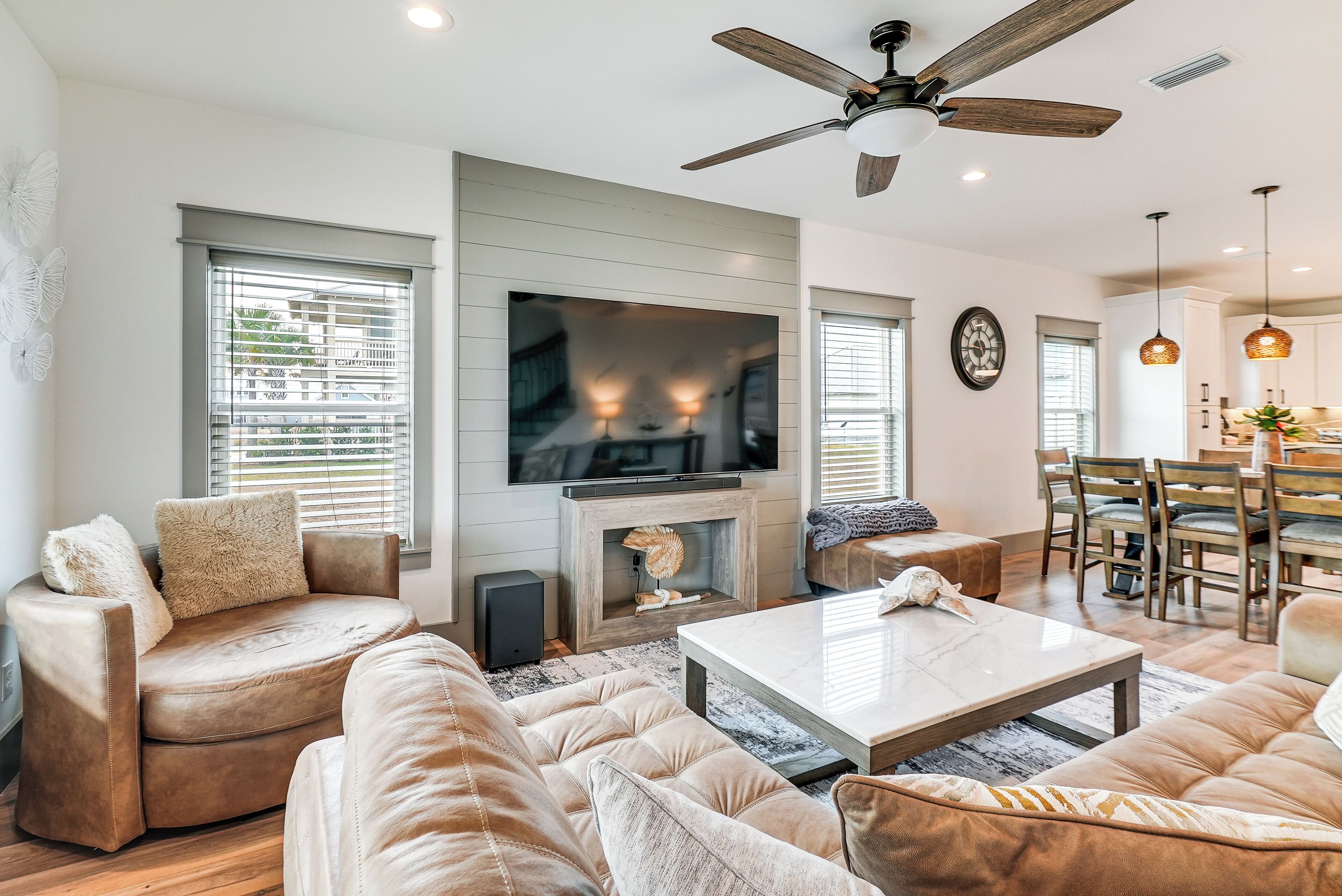 A modern living room with a fireplace, comfortable seating, a television, and a dining area.