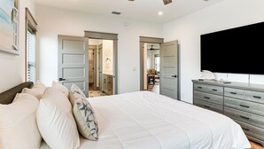 A bedroom with a large bed, a dresser, and a flat-screen TV. - Walk to Beach! 'ocean's Paradise' w/ Patio (Port St. Joe)
