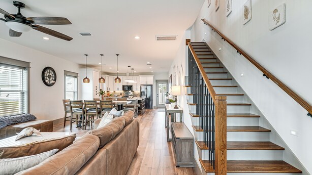 A spacious living area with a wooden staircase, a large sofa, and a dining area. - Walk to Beach! 'ocean's Paradise' w/ Patio (Port St. Joe)